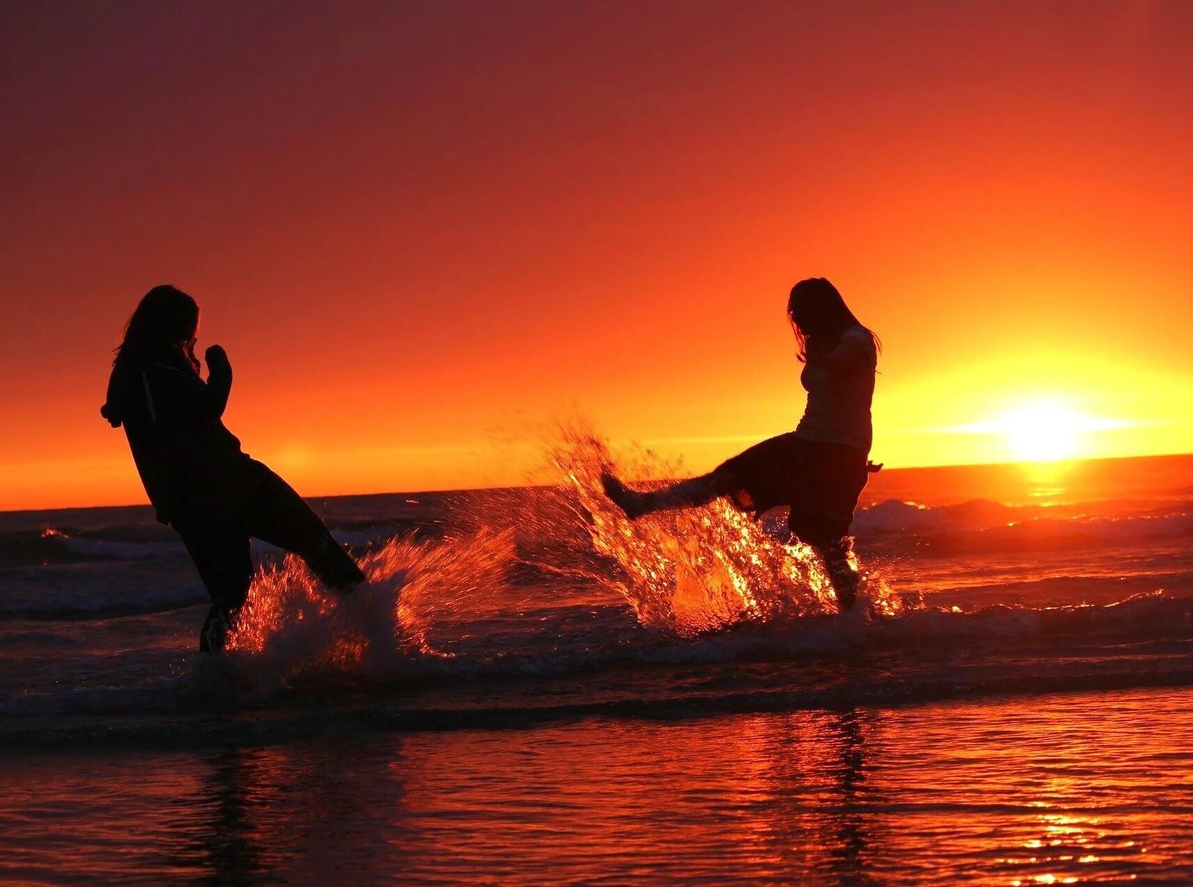 Women playing on beach at sunset